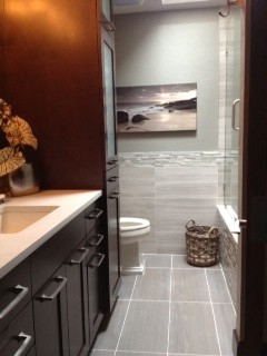 Mid-sized transitional 3/4 bathroom in Seattle with an undermount sink, furniture-like cabinets, dark wood cabinets, engineered quartz benchtops, an alcove tub, an alcove shower, a two-piece toilet, gray tile, mosaic tile, grey walls and porcelain floors.