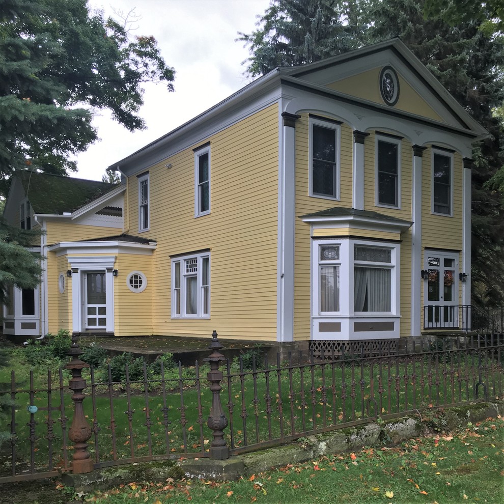 This is an example of a large traditional two-storey yellow exterior in New York with concrete fiberboard siding and a gable roof.