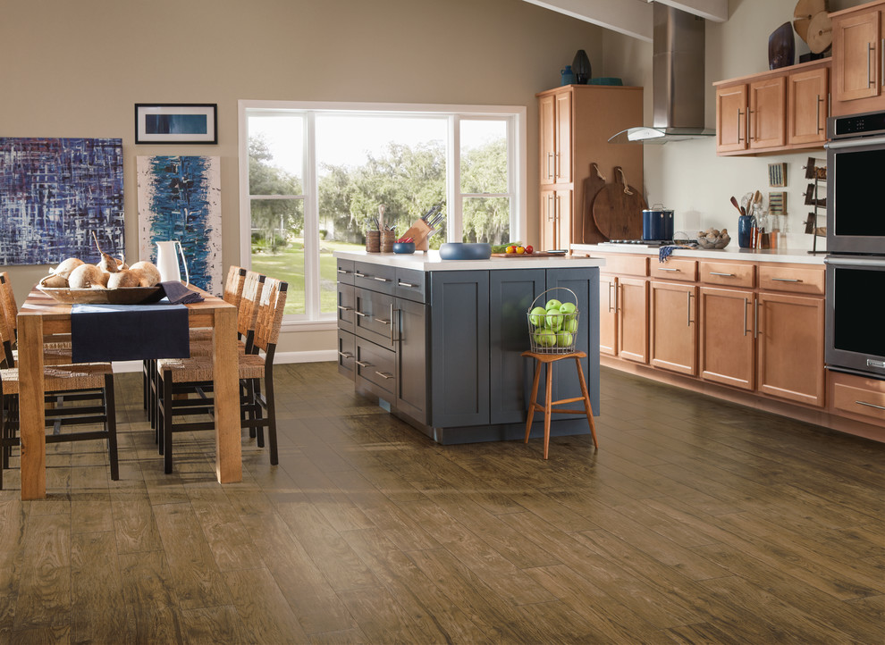 Example of a mid-sized transitional single-wall vinyl floor eat-in kitchen design with shaker cabinets, medium tone wood cabinets, stainless steel appliances and an island