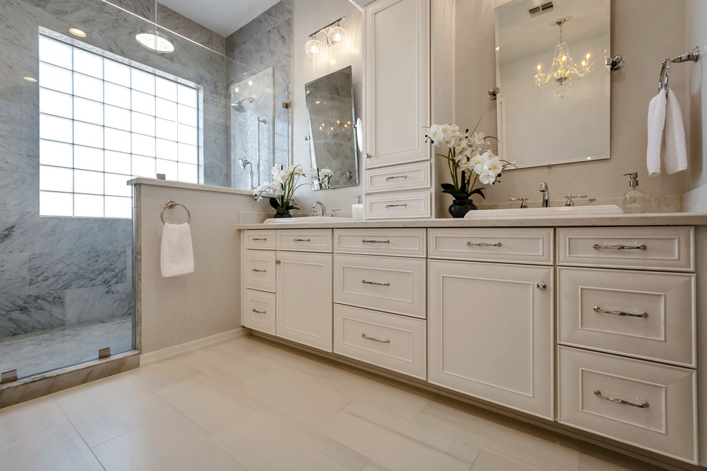 Example of a large transitional master gray tile and marble tile porcelain tile and gray floor freestanding bathtub design in Phoenix with recessed-panel cabinets, white cabinets, gray walls, a drop-in sink, quartz countertops and white countertops