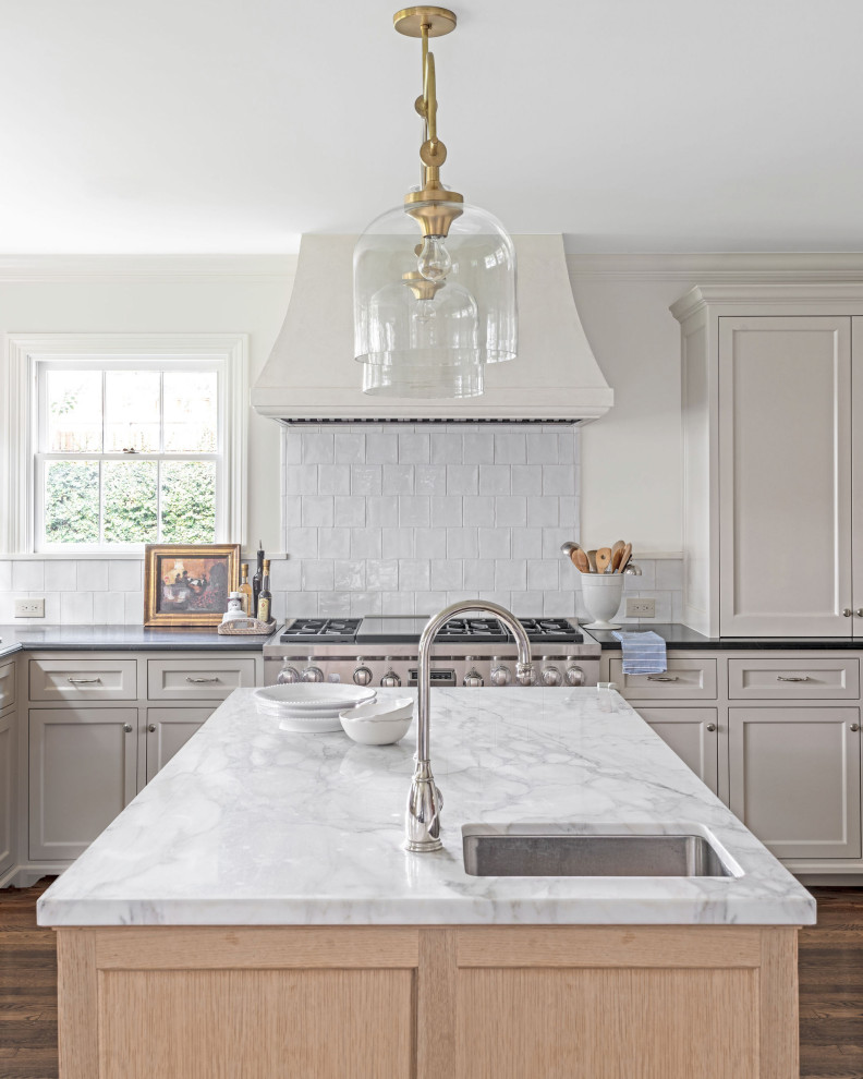 Design ideas for a mid-sized traditional l-shaped separate kitchen in Houston with an undermount sink, beaded inset cabinets, beige cabinets, marble benchtops, white splashback, ceramic splashback, panelled appliances, dark hardwood floors, with island, brown floor and white benchtop.