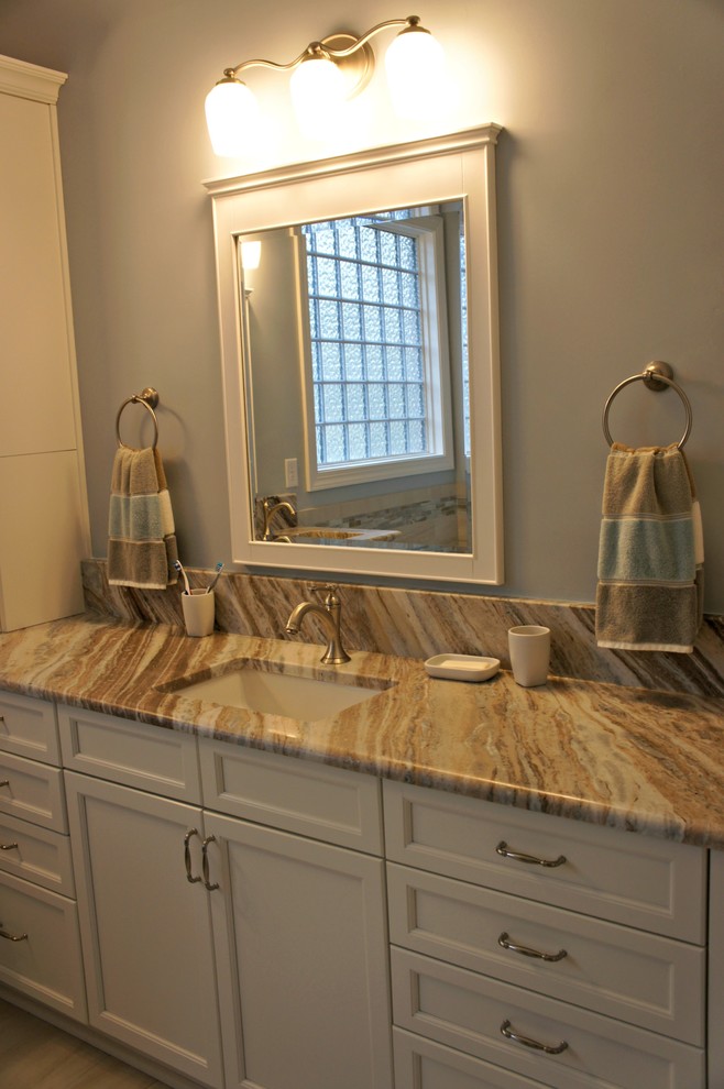 Photo of an arts and crafts master bathroom in Raleigh with flat-panel cabinets, white cabinets, a drop-in tub, beige tile, ceramic tile, blue walls, ceramic floors, an undermount sink and marble benchtops.