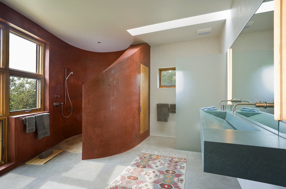 Mid-sized contemporary master bathroom in Albuquerque with open cabinets, an open shower, a one-piece toilet, brown tile, stone tile, red walls, concrete floors, a trough sink and concrete benchtops.