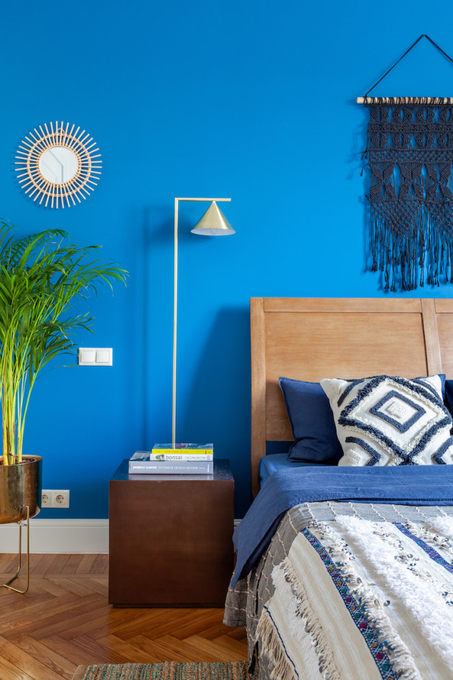 Réalisation d'une chambre parentale bohème de taille moyenne avec un mur bleu et un sol en bois brun.
