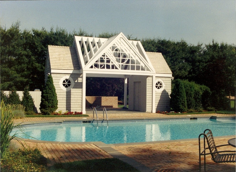 This is an example of a mid-sized transitional backyard round lap pool in New York with a pool house and brick pavers.