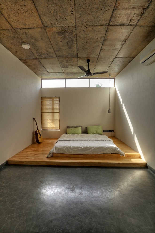 Industrial bedroom in Other with white walls, medium hardwood floors and grey floor.