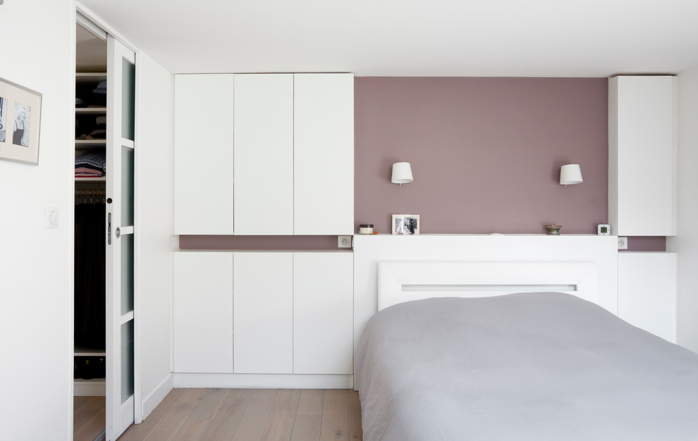 Photo of a contemporary master bedroom in Paris with white walls and light hardwood floors.