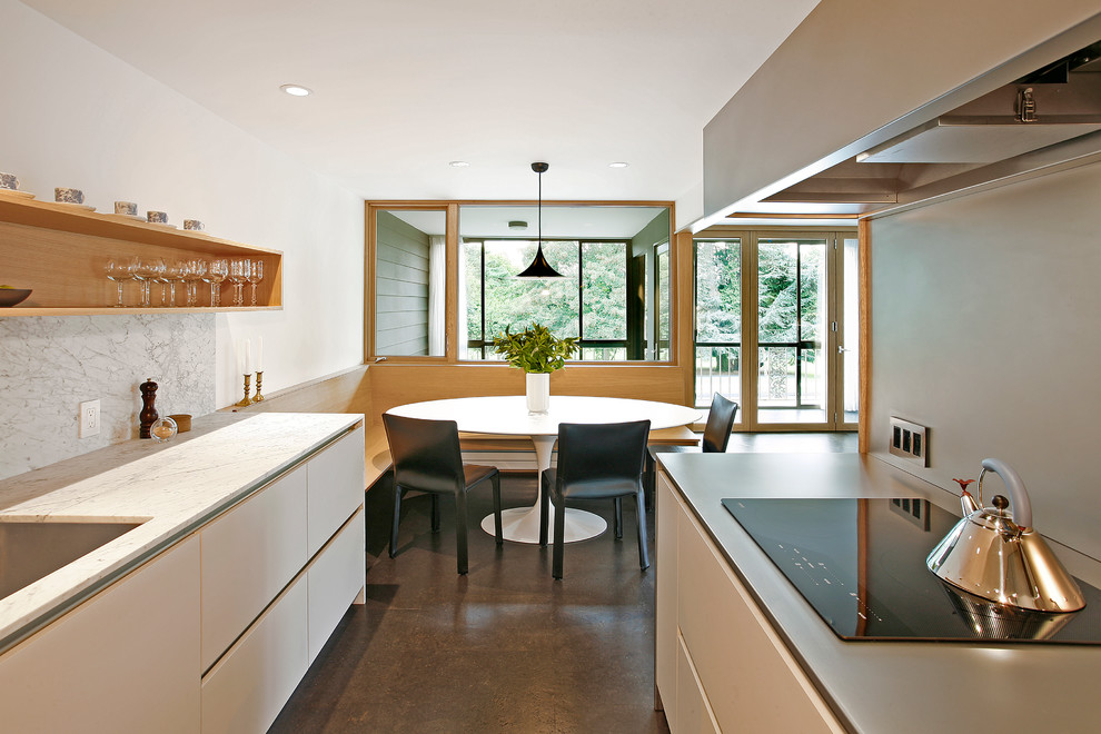 Inspiration for a mid-sized midcentury l-shaped eat-in kitchen in Seattle with an undermount sink, flat-panel cabinets, white cabinets, solid surface benchtops, stainless steel appliances and cork floors.