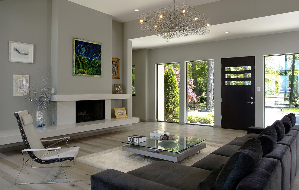 This is an example of a large contemporary living room in Grand Rapids with grey walls, light hardwood floors, a standard fireplace and a concrete fireplace surround.