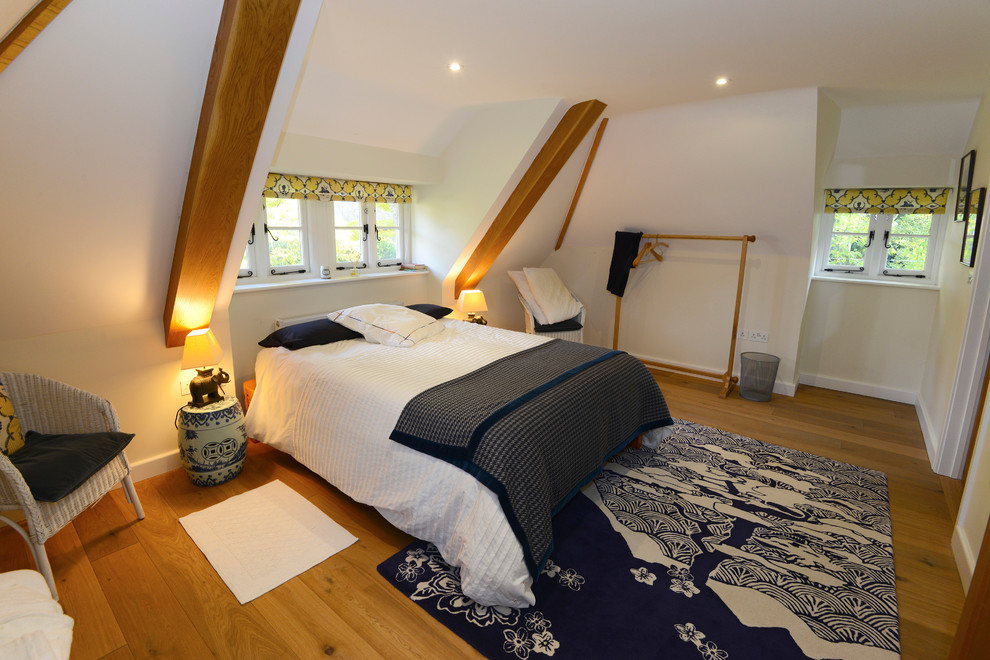 Design ideas for a mid-sized asian guest bedroom in Wiltshire with white walls and light hardwood floors.