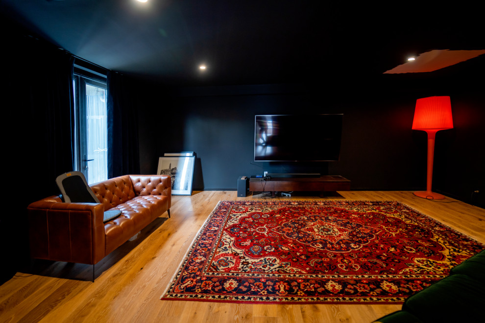 This is an example of a large asian enclosed home theatre in Sydney with black walls, light hardwood floors, a wall-mounted tv and brown floor.