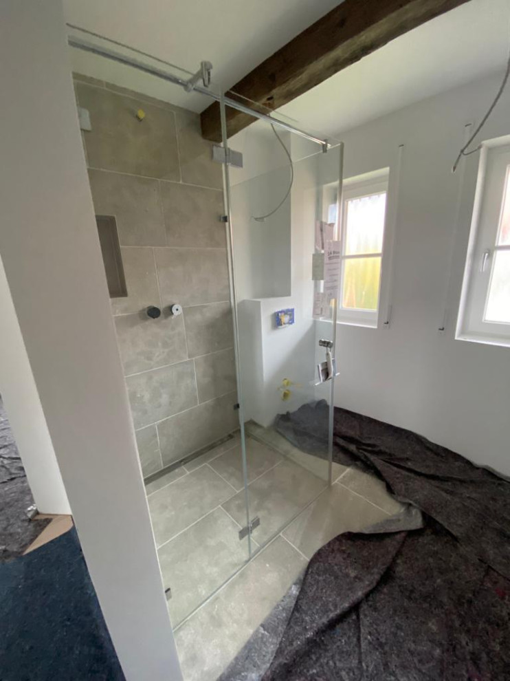 Badezimmer mit offenen Schränken, Schränken im Used-Look, bodengleicher Dusche, grauen Fliesen, Steinplatten, Kalkstein, Aufsatzwaschbecken, Kalkstein-Waschbecken/Waschtisch, grauem Boden, Falttür-Duschabtrennung, Einzelwaschbecken und Steinwänden in Munich