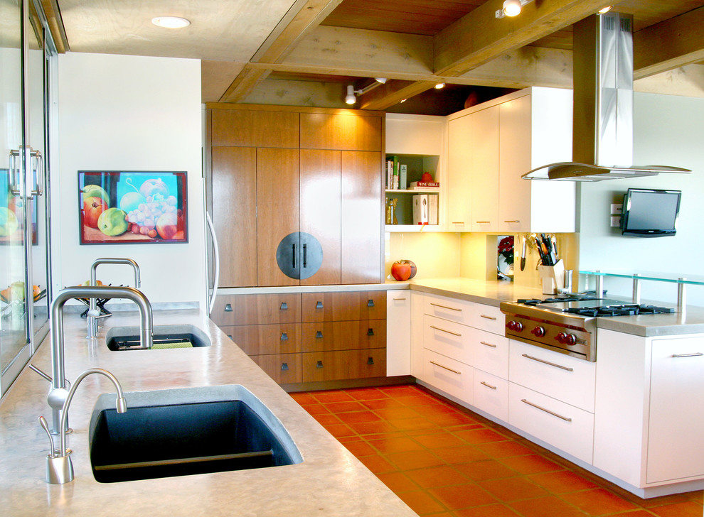 This is an example of a mid-sized contemporary u-shaped open plan kitchen in Austin with an undermount sink, flat-panel cabinets, white cabinets, concrete benchtops, green splashback, glass sheet splashback, stainless steel appliances, terra-cotta floors, a peninsula and pink floor.