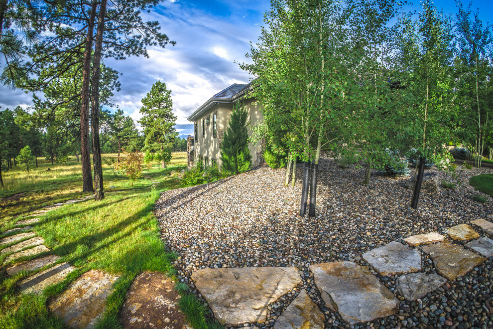Photo of a large traditional backyard shaded xeriscape for fall in Denver with a garden path and natural stone pavers.