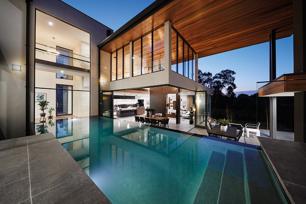 Inspiration for a large contemporary backyard rectangular infinity pool in Melbourne with a water feature and tile.