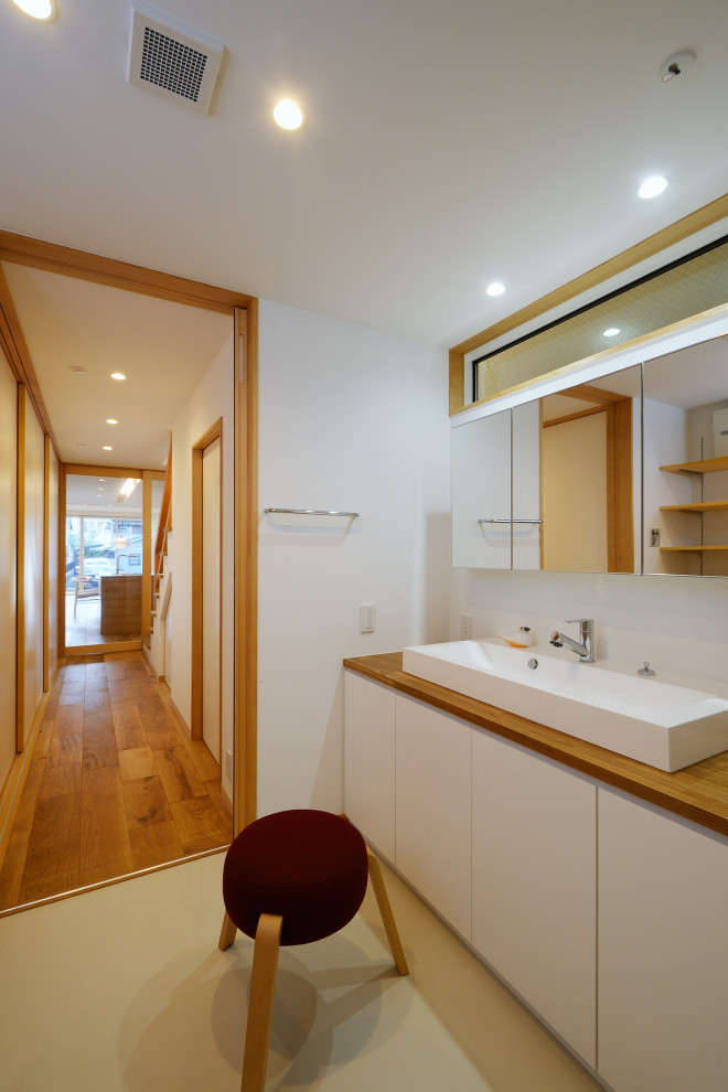 Idéer för funkis vitt toaletter, med skåp i ljust trä, vit kakel, vita väggar, vinylgolv och grått golv