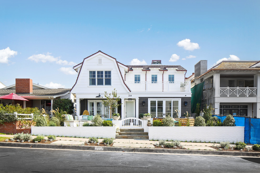 Photo of a beach style two-storey white house exterior in Los Angeles with mixed siding and a gambrel roof.