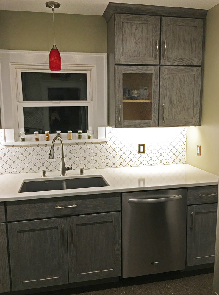 Example of a small transitional galley enclosed kitchen design in Seattle with an undermount sink, shaker cabinets, gray cabinets, quartzite countertops, white backsplash, ceramic backsplash, stainless steel appliances and no island