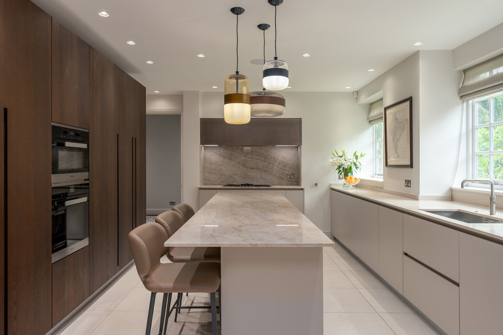 This is an example of a large transitional separate kitchen in London with an undermount sink, flat-panel cabinets, dark wood cabinets, marble benchtops, beige splashback, marble splashback, stainless steel appliances, ceramic floors, with island, white floor and beige benchtop.