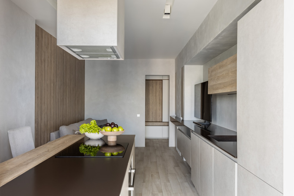 Medium sized contemporary grey and white galley open plan kitchen in Saint Petersburg with an integrated sink, flat-panel cabinets, beige cabinets, composite countertops, grey splashback, black appliances, ceramic flooring, an island, beige floors and brown worktops.