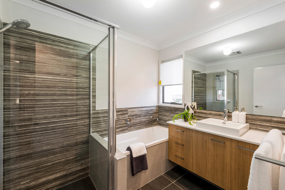 Design ideas for a mid-sized contemporary 3/4 bathroom in Brisbane with flat-panel cabinets, light wood cabinets, a drop-in tub, a corner shower, a one-piece toilet, black tile, ceramic tile, grey walls, ceramic floors, a vessel sink and engineered quartz benchtops.