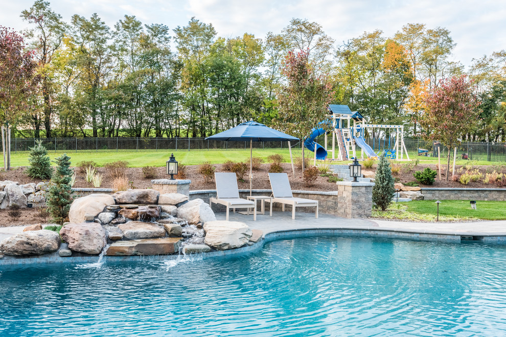 Inspiration for a large transitional backyard concrete paver and custom-shaped pool remodel