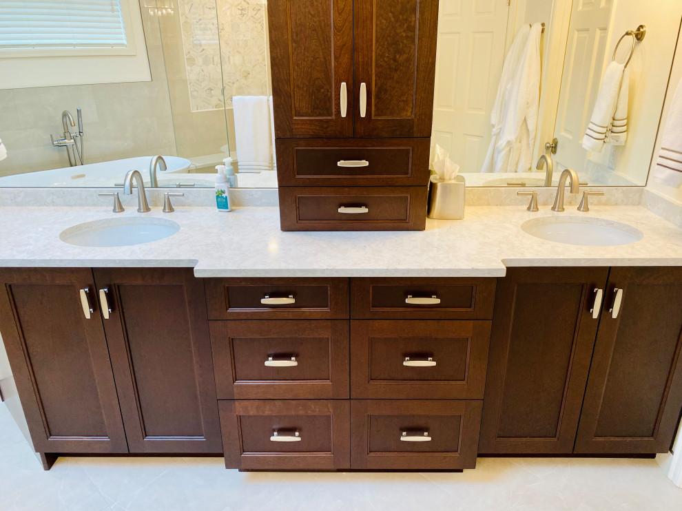 Photo of a mid-sized traditional master bathroom in Seattle with shaker cabinets, dark wood cabinets, a freestanding tub, a corner shower, beige tile, porcelain tile, beige walls, porcelain floors, an undermount sink, engineered quartz benchtops, beige floor, a hinged shower door, beige benchtops, a shower seat, a double vanity and a built-in vanity.