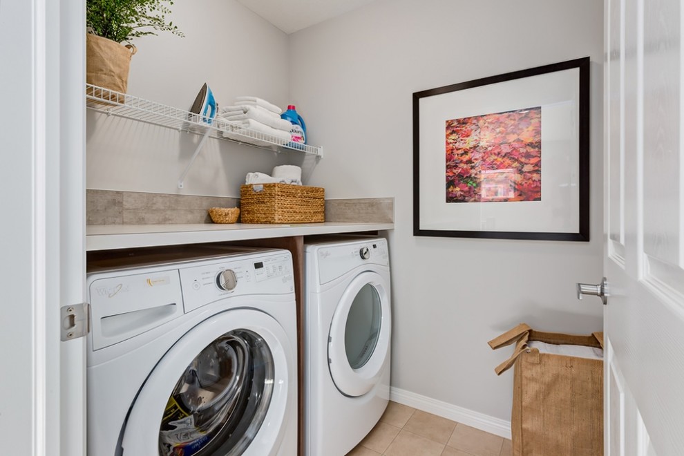 This is an example of a mid-sized traditional single-wall dedicated laundry room in Calgary with grey walls, a side-by-side washer and dryer and beige floor.