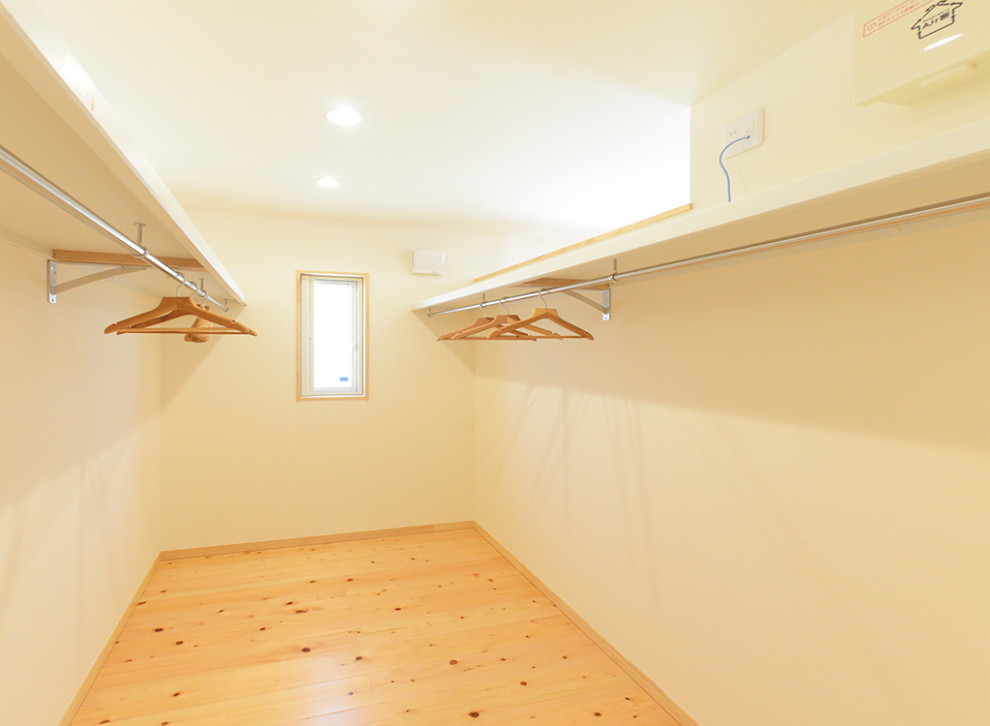 Idee per una grande cabina armadio unisex etnica con pavimento in legno massello medio e pavimento beige