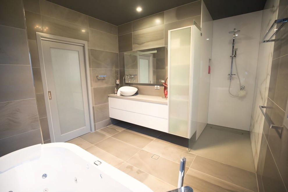 This is an example of a mid-sized contemporary master bathroom in Canberra - Queanbeyan with glass-front cabinets, a freestanding tub, an alcove shower, gray tile, marble, marble floors, a vessel sink, granite benchtops, grey floor and an open shower.