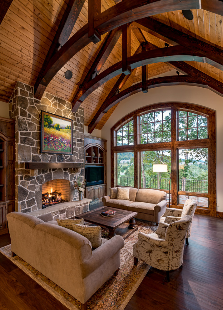 Inspiration for a country living room in Other with grey walls, dark hardwood floors, a standard fireplace, a stone fireplace surround and brown floor.
