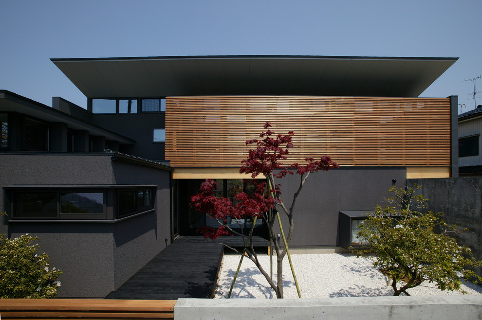 Photo of a mid-sized asian two-storey black house exterior in Other with mixed siding and a flat roof.