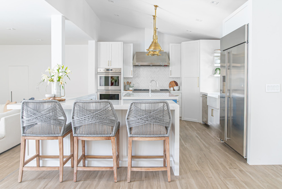 This is an example of a transitional u-shaped open plan kitchen in Other with a farmhouse sink, shaker cabinets, white cabinets, multi-coloured splashback, medium hardwood floors, with island, brown floor and vaulted.