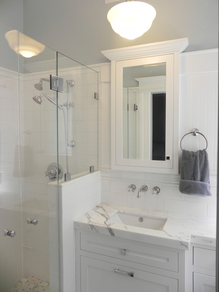 Photo of a small traditional master bathroom in San Francisco with shaker cabinets, white cabinets, an alcove shower, white tile, ceramic tile, blue walls, mosaic tile floors, an undermount sink, marble benchtops and a one-piece toilet.