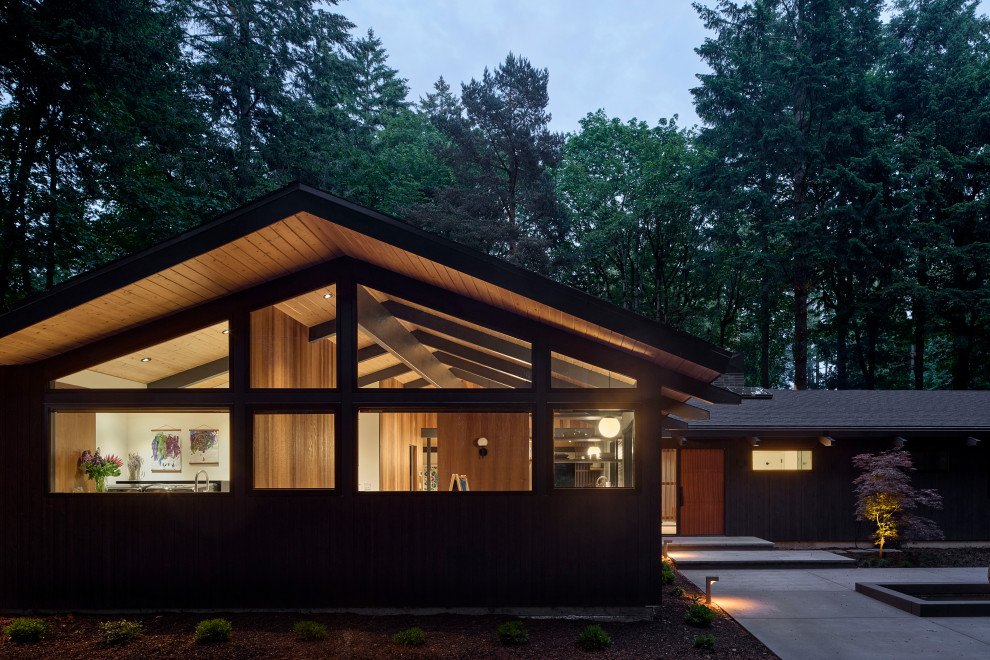 Example of a large 1960s black one-story wood exterior home design in Portland with a shingle roof and a black roof