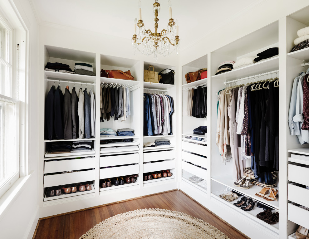 Inspiration for a mid-sized transitional gender-neutral medium tone wood floor and brown floor walk-in closet remodel in New York with flat-panel cabinets and white cabinets