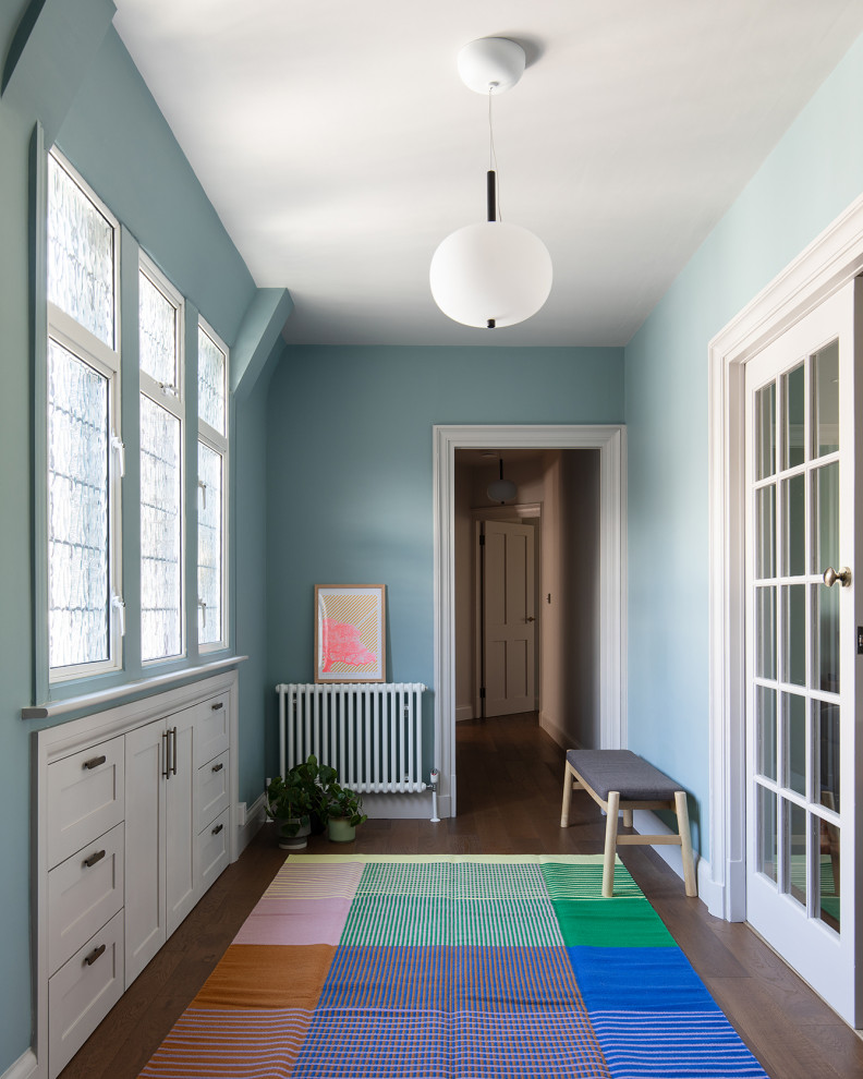 Idee per un corridoio design di medie dimensioni con pareti blu, parquet scuro, una porta a pivot, una porta in metallo e pavimento marrone