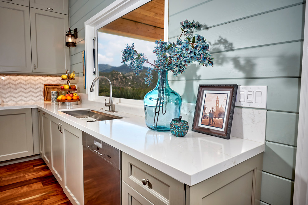 Example of a large transitional l-shaped medium tone wood floor and brown floor open concept kitchen design in Denver with an undermount sink, recessed-panel cabinets, gray cabinets, quartz countertops, white backsplash, marble backsplash, stainless steel appliances, an island and white countertops
