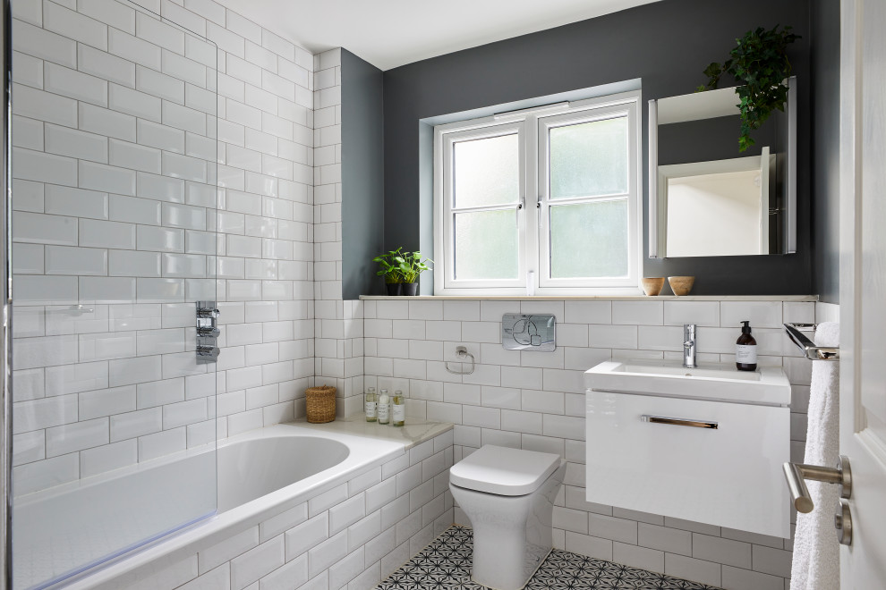 Photo of a medium sized traditional family bathroom in London with glass-front cabinets, white cabinets, a built-in bath, a built-in shower, a one-piece toilet, white tiles, ceramic tiles, green walls, ceramic flooring, a console sink, quartz worktops, multi-coloured floors, white worktops, a single sink and a floating vanity unit.