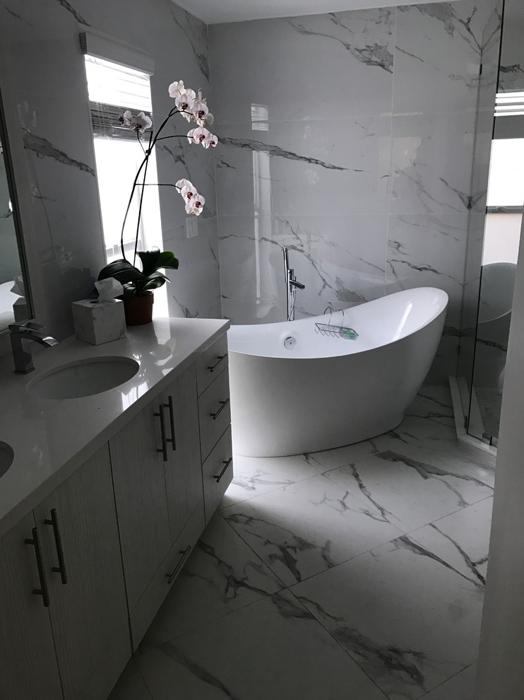 Mid-sized contemporary master bathroom with flat-panel cabinets, white cabinets, a freestanding tub, a corner shower, gray tile, marble, grey walls, marble floors, an undermount sink, quartzite benchtops, grey floor and a hinged shower door.