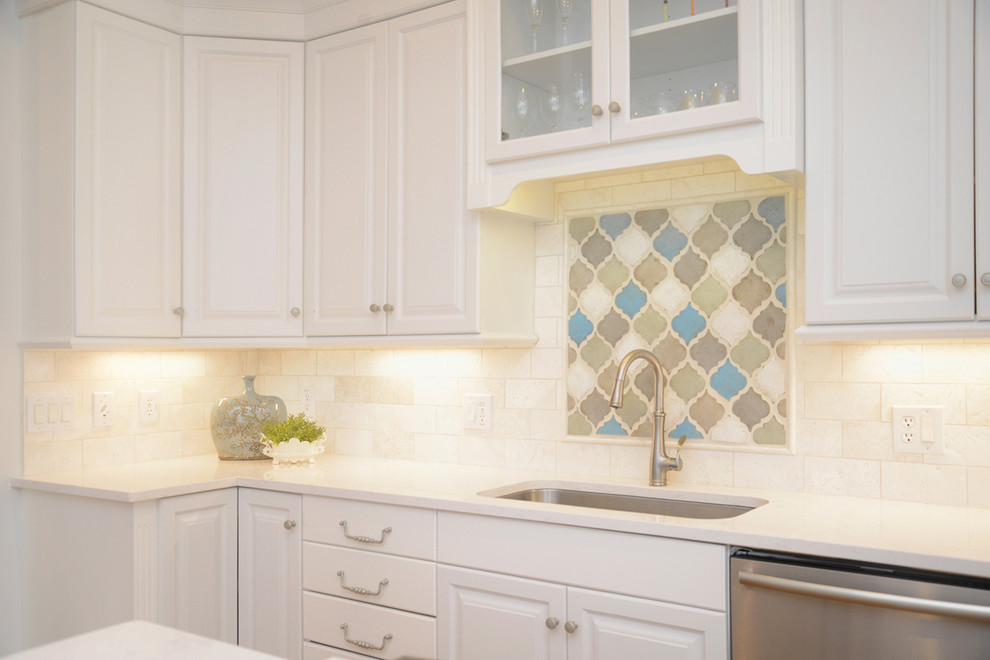 Transitional light wood floor kitchen photo with white cabinets, beige backsplash, stainless steel appliances and an island