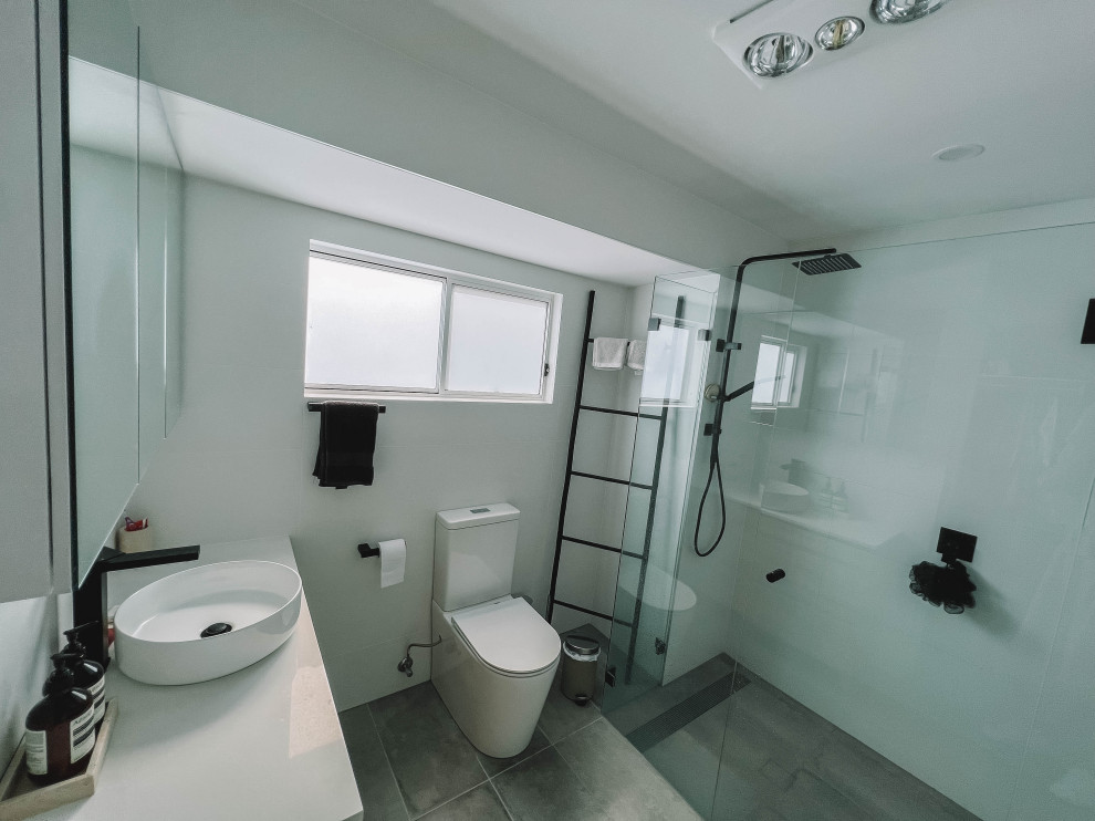 Idéer för mellanstora skandinaviska vitt en-suite badrum, med släta luckor, skåp i ljust trä, en kantlös dusch, en toalettstol med hel cisternkåpa, vit kakel, keramikplattor, vita väggar, klinkergolv i keramik, ett fristående handfat, bänkskiva i kvarts, grått golv och dusch med gångjärnsdörr