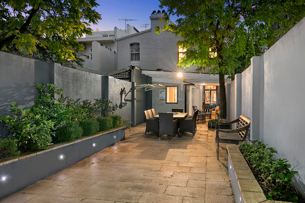 This is an example of a traditional backyard garden in Sydney with a container garden and natural stone pavers.