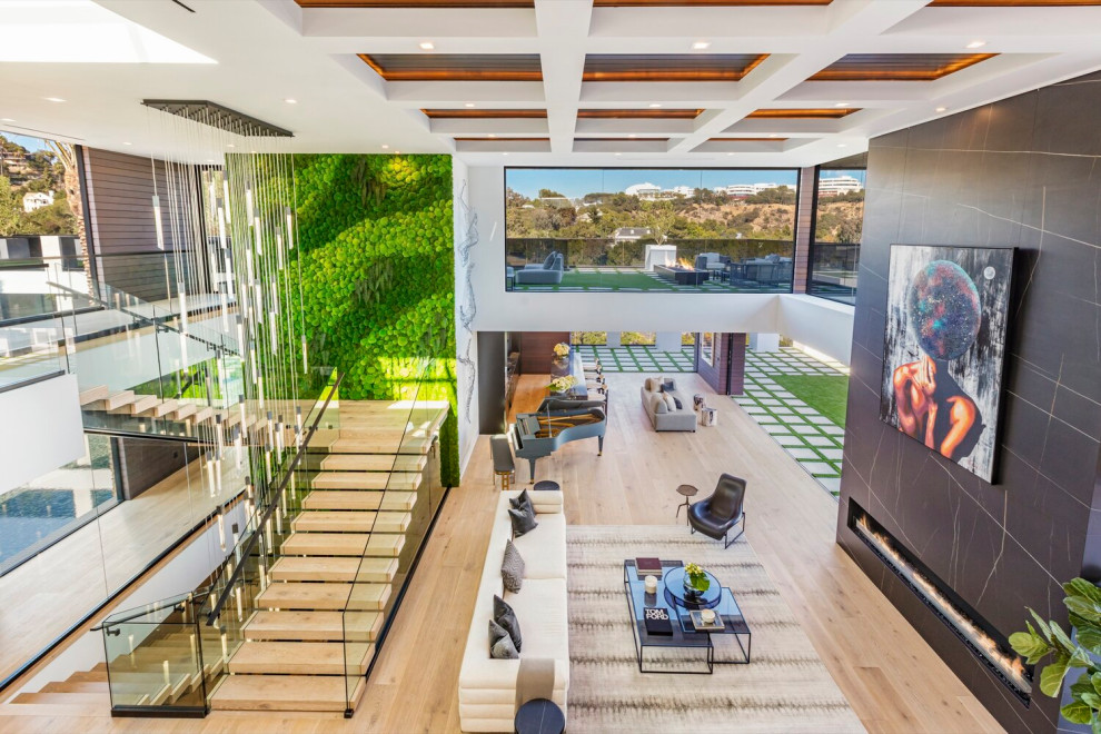 Photo of an expansive modern open concept living room in Los Angeles with a home bar, white walls, a standard fireplace, a stone fireplace surround, no tv, beige floor and recessed.