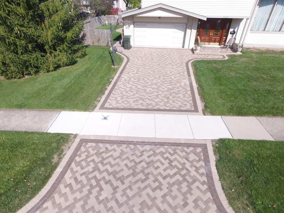 Photo of a large traditional front yard full sun driveway in Chicago with natural stone pavers.