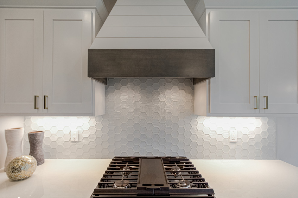 Open concept kitchen - large transitional l-shaped medium tone wood floor open concept kitchen idea with flat-panel cabinets, white cabinets, quartz countertops, white backsplash, glass tile backsplash, black appliances and beige countertops