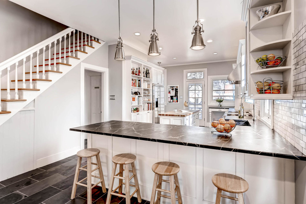 Design ideas for a large transitional l-shaped open plan kitchen in Denver with a farmhouse sink, recessed-panel cabinets, white cabinets, soapstone benchtops, grey splashback, subway tile splashback, stainless steel appliances, ceramic floors and with island.