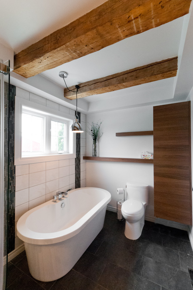 This is an example of a small eclectic master bathroom in Montreal with flat-panel cabinets, medium wood cabinets, laminate benchtops, a freestanding tub, a corner shower, gray tile, ceramic tile and ceramic floors.