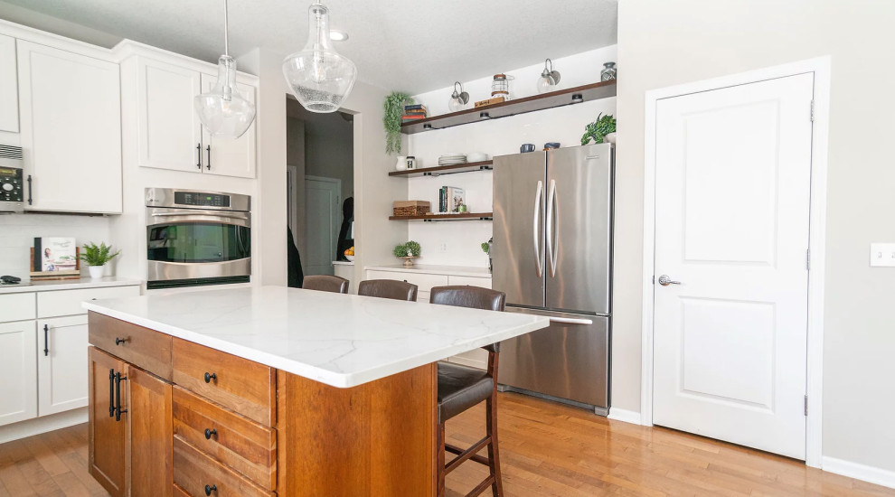 Inspiration for a large transitional u-shaped medium tone wood floor and brown floor eat-in kitchen remodel in Minneapolis with a single-bowl sink, shaker cabinets, white cabinets, quartz countertops, white backsplash, porcelain backsplash, stainless steel appliances, an island and white countertops