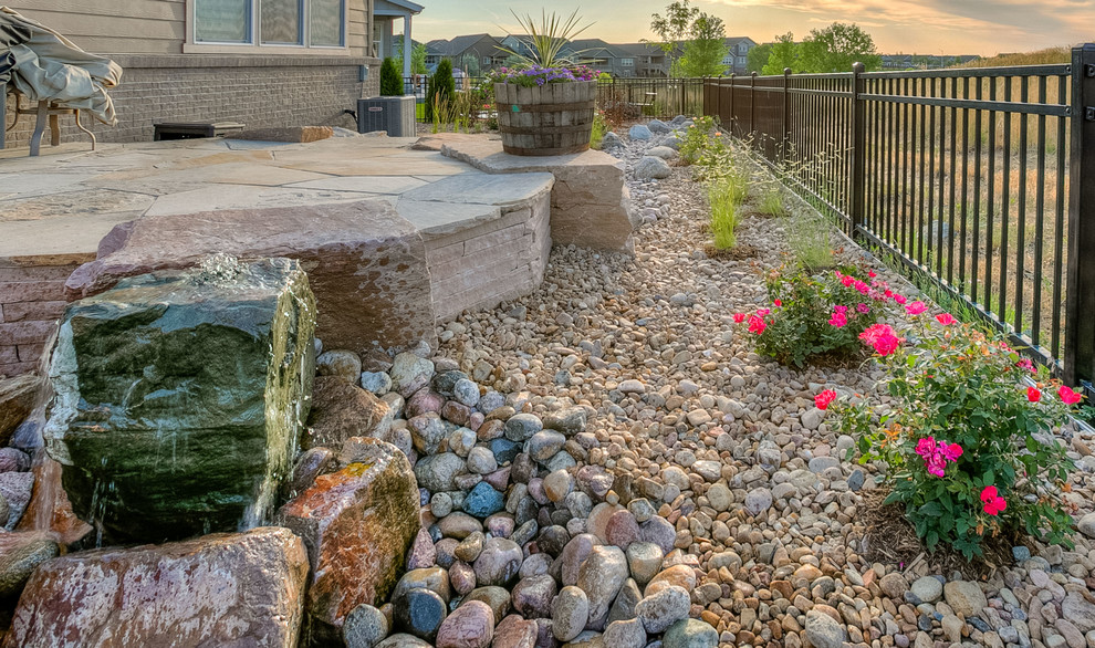 Large and desert look backyard partial sun xeriscape in Denver with natural stone pavers.